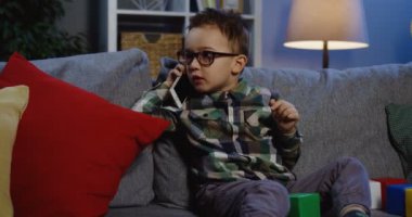 telefon kullanarak gözlüklü küçük okul çocuğu