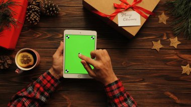 Yukarıdan onun beyaz tablet chroma key, ahşap masa, Noel ruh hali, yeşil ekran üzerinde kaydırma adam hareket izleme görüntülemek