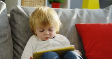 Portre tatlı küçük çocuk çizgi film tablet bilgisayarda evde kanepede otururken izlemek bir kadeh. Kapalı