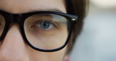 Mavi gözlü bardaklarda yarım erkek yüz. Yakın çekim. Arka plan bulanık.