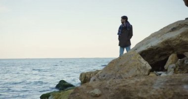 Paltonu ve kaşkolünü sahil buzlu üzerinde duran güzel adam. Bulutlu gökyüzü ve soğuk hava. Açık havada