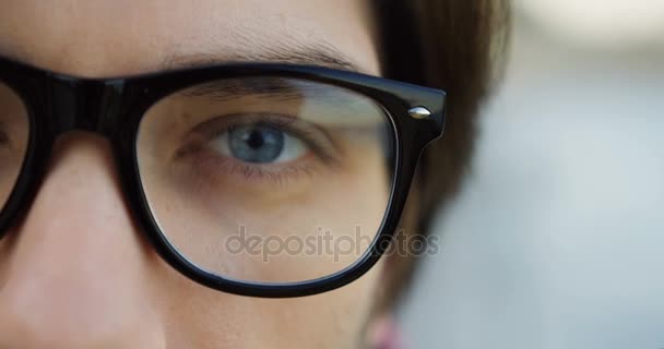 Half male face in glasses with blue eyes. Close up. Blurred background. — Stock Video