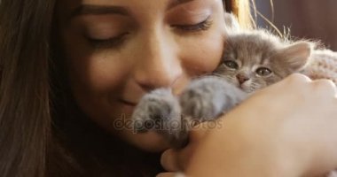 Sevecen ve onun küçük gri kedicik sarılma ve o öpüşme çekici genç kadın. Portre vurdu. Yakın çekim. Kapalı