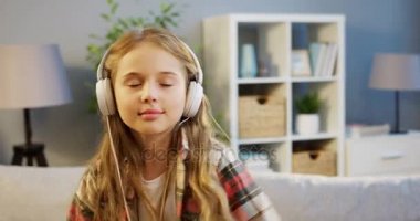 Büyük kulaklık müzik ve arazide ile rahatlatıcı sevimli sarışın kız portre rahat odaya taşır. Kapalı