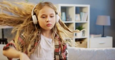 Büyük beyaz kulaklık müzik ve ritim evde güzel odasında hareketli güzel sarışın kız portre vurdu. İçinde