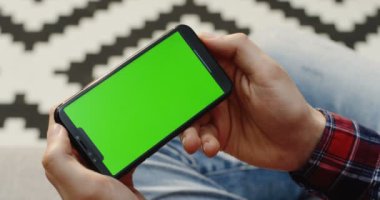 Siyah smartphone yatay olarak bulanık desen halı arka planda tutan erkek el kapatın. Üstten Görünüm. Yeşil ekran. Chroma anahtar.