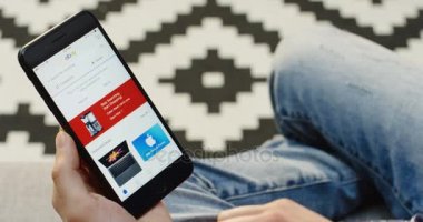 New York - 01 Aralık 2017: beyaz erkek eller siyah bir akıllı telefon tutuyor ve Ebay uygulaması kullanıyor. Omzundan. Düzenli arkaplan.