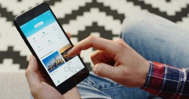 New York - 01 Aralık 2017: siyah bir akıllı telefon tutarak ve Trip Advisor uygulama üzerinde kaydırma beyaz eller Mans. Omuz üzerinden. Pattered halı arka plan. Yakın çekim