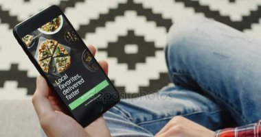 New York - 01 Aralık 2017: dikey olarak siyah bir akıllı telefon tutarak ve Uber yiyor app kullanarak erkek eller. Omuz üzerinden. Desenli arka plan. Yakın çekim