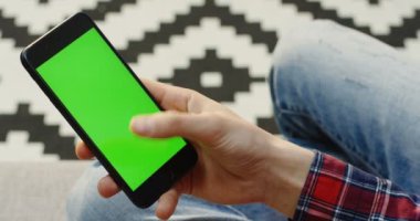 Omuz ile erkek elinde yeşil ekran siyah akıllı telefon üzerinde hangi kaydırma ve üzerinde kaydediyor. Dikey olarak. Chroma anahtar