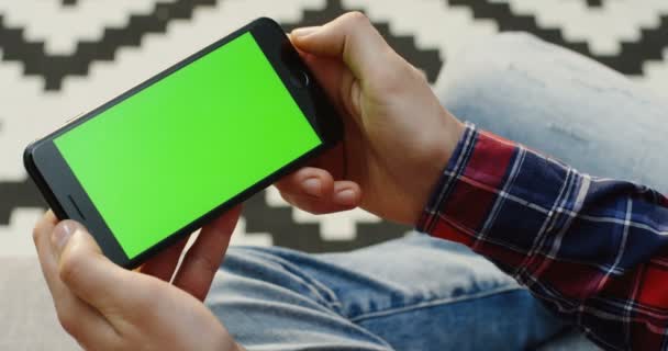緑の画面のスマートフォンを水平方向に手の人の手を閉じます。クロマキー。肩越しに — ストック動画