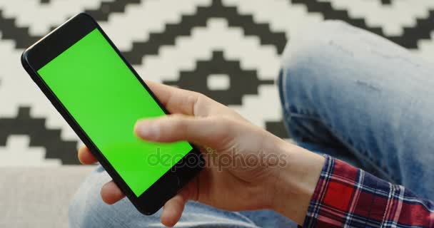 über der Schulter auf dem schwarzen Smartphone mit grünem Bildschirm in Männerhänden, die darauf scrollen und kleben. vertikal. Chroma-Schlüssel