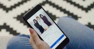 New York - 01 Aralık 2017: kaydırma ve Aliexpress app dikey siyah akıllı telefonda giysiler seçmek eller. Patterened halı üzerinde arka plan bulanık. Üstten Görünüm. Yakın çekim