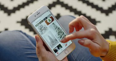 New York - 01 Aralık 2017: beyaz kadının ellerini beyaz smartphone cep telefonu ile Pinterest uygulama fotoğraflarda kaydırma. Arka plan bulanık. Yakın çekim