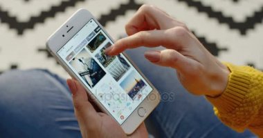 New York - 01 Aralık 2017: Dikey beyaz smartphone üzerinde Pinterest uygulaması üzerinde kaydırma Kafkas kadın el yakın. Desenli arka plan bulanık.