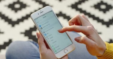 New York - 01 Aralık 2017: Akıllı telefon setttings kaydırma ve Touch kimliği programı seçme kadının el yakın. Üstten Görünüm. Bulanık kat arka plan