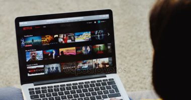 New York - 01 Aralık 2017: Üzerinden yakın omuz görünümü Netflix Web sitesinde kaydırma ve dizüstü bilgisayar bir film izlerken başlayan beyaz bir kadın. Üstten Görünüm