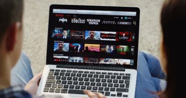 New York - 01 Aralık 2017: Kafkas erkek ve kadın Netflix web sitesinde kayan üst omuz görünümünü kapatın ve dizüstü bilgisayardan bir dizi izlemeye başlayın. Üst görünüm