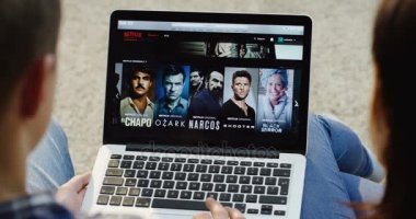 New York - 01 Aralık 2017: Beyaz adam ve kadın diz yalan dizüstü bilgisayarda Netflix sitesinde kaydırma omuz görünümü. Yakın çekim. Üstten Görünüm