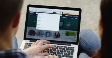 New York - 01 Aralık 2017: Close up üzerinden omuz görünümü kadın ve bazı ürünler seçmek için dizüstü bilgisayar üzerinde Amazon Web kullanan adam. Üstten Görünüm