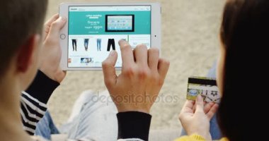 New York - 01 Aralık 2017: üzerinde omuz görünümü giyim çift internetten kredi kartıyla yakın tablet bilgisayarda Amazon Web sitesinde. Üstten Görünüm