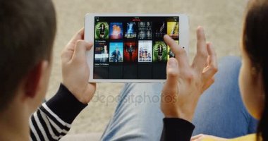 New York - 01 Aralık 2017: Üzerinden yakın omuz görünümü üzerinde beyaz adam ve Netflix Web sitesinde kaydırma ve bir seri yatay beyaz tablet izlemeye başlayan kadın. Üstten Görünüm