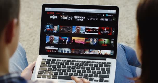 New York - 01 Aralık 2017: Kafkas erkek ve kadın Netflix web sitesinde kayan üst omuz görünümünü kapatın ve dizüstü bilgisayardan bir dizi izlemeye başlayın. Üst görünüm — Stok video