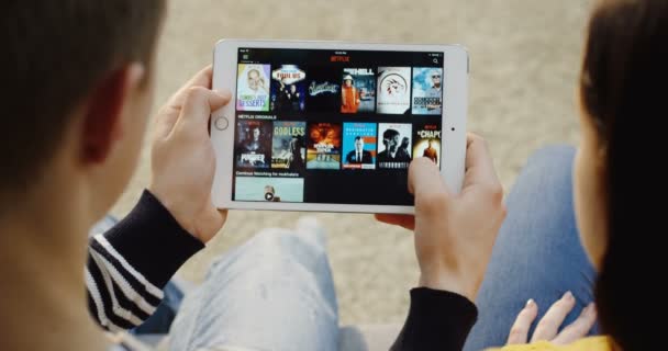 New York - Dec 01, 2017: Over shoulder view on the Caucasian man and woman scrolling on the Netflix website on the tablet computer Close up Top view
