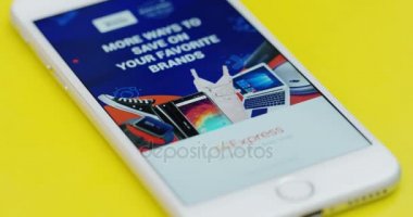 New York - 01 Aralık 2017: Erkek parmak Aliexpress app açma ve içinde sarı masanın üzerinde yatan beyaz smartphone cep telefonu ile kaydırma yakın.
