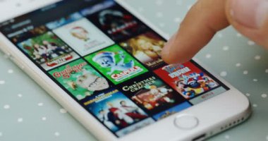 New York - 01 Aralık 2017: erkek parmak tomar masanın üzerinde yatan beyaz smartphone cep telefonu ile Netflix app Filmler listesinde. Yakın çekim