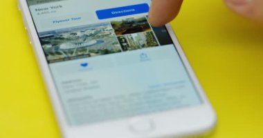 New York - 01 Aralık 2017: Close up haritalar'ı kullanmakta erkek parmak app akıllı beyaz telefon hangi sarı masanın üzerinde yatan.
