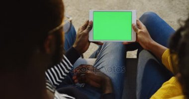 Afrika kökenli Amerikalı çift üzerinde omuz görünümü üzerinde beyaz tablet mermiyi yeşil ekran ile yatay olarak gördükleri tartışırken, kaydırma ve üzerinde kayıt tutuyor. Yakın çekim