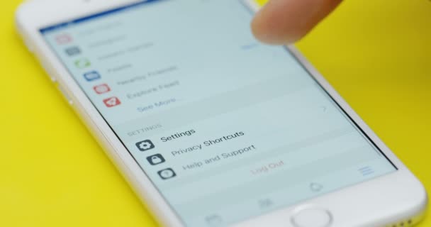 Nova Iorque - Dezembro 01, 2017: Mans dedo rolando em sua página de configurações de smartphone branco na mesa amarela. Fechar — Vídeo de Stock