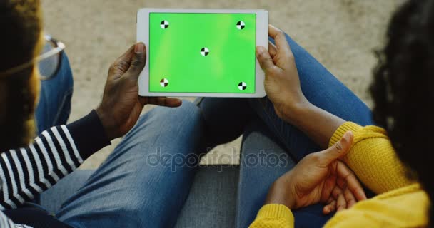 African American man och kvinna som håller en vit tablett dator med grön skärm horisontellt och kvinna rullning och tejpa på den. Färgtransparens. Spåra rörelse. Över axeln. Närbild — Stockvideo