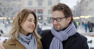 Orta yaş hagging ve kentin kamera önünde karlı gününde gülümseyen çekici çift portresi. Yakın çekim. Açık havada