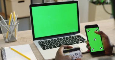 Üzerinden yakın omuz görünümü kaydırma ve yeşil ekran ve hareket üzerinde izleme ve süre alışveriş online kredi kartı elinde siyah bir smartphone taping Afrikalı-Amerikalı adam