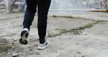 Arkadan görünüş sportif adam boks torbası yaklaşıyor ve sisli gün atılmış binanın dışında tekmelemeye başladı. Arka. Yakın çekim