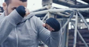 Çekici adamın sakallı ve sportif giysiler kırmızı boks torbasına terk edilmiş binalar alan üzerinde soğuk sisli sabahı tekmeleme kapatın. Açık havada