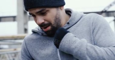 Genç adam bir boks kırmızı çanta ile güçlü bir motivasyon tekme ve soğuk sisli günde yüz konsantre kapatın. Bitki kalıntıları. Açık havada