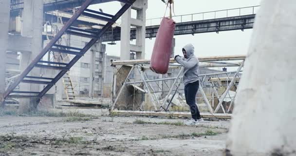 Caucasian Man Sporty Clothes Punching Bag Abandoned Factory Cold Misty — Stock Video