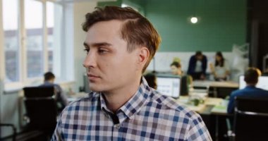 Genç yakışıklı beyaz adam kafasını çevirerek ve kentsel office kamerada bakarak kapatın. Çalışma insanlar üzerinde arka plan bulanık. Portre vurdu