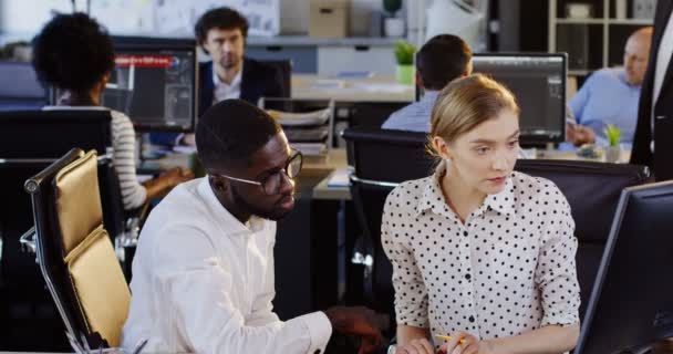 Jóvenes razas mixtas empleados que trabajan en la computadora y ser revisados por su jefe de su trabajo mientras trabajan en la computadora. Oficina urbana sobre fondo borroso. Adentro. — Vídeos de Stock