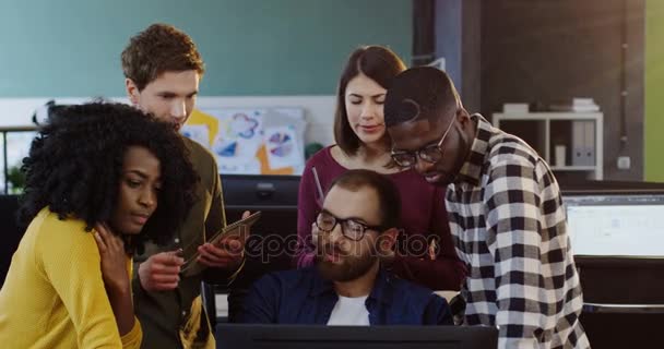 Jeune entreprise mixte équipe en consultation avec leur jeune patron au sujet d'un projet. Femmes et hommes debout et regardant l'ordinateur dans le bureau moderne  . — Video