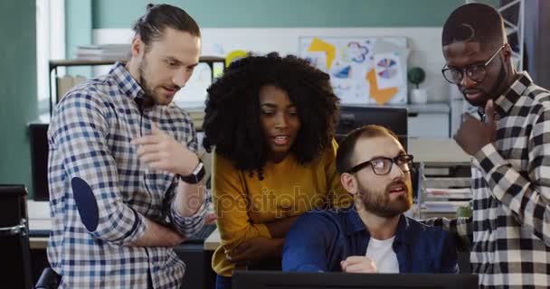 Giovane team multietnico di lavoratori che parla e crea un business plan per un progetto al computer. Ufficio squadra di uomini e donne nella confortevole sala ufficio . — Video Stock