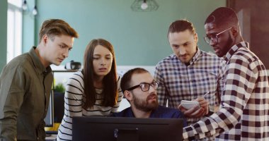 Genç dostu çok etnik gruptan oluşan Ofis çalışanları bilgisayarda bir başlangıç projesi için bir strateji oluşturma. Erkek ve kadında rahat güzel ofis alanı Office ekibi.