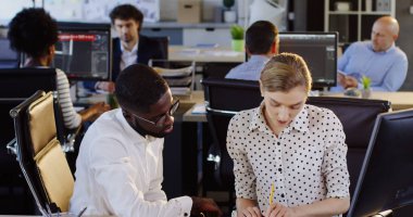 Genç yarış çalışanların çalışma bilgisayar ve bilgisayarda çalışırken işlerini kendi patronu tarafından denetlenen karışık. Kentsel ofisi arka plan bulanık. İçinde