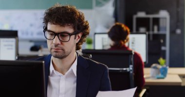 Bilgisayar başında oturan ve modern ofis Oda Yazdırılan belgelerde birlikte çalışma erkek ofis çalışanı. Kapalı