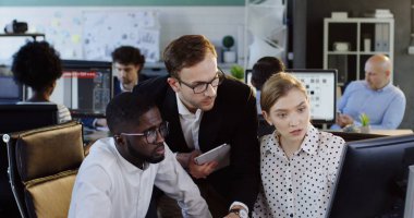 Genç karışık ırklar birkaç office ortak çalışanlar büyük konforlu ofis bölgesi bilgisayara otururken onların iş projesi ile bir üst düzey yönetici tartışıyor. Kapalı