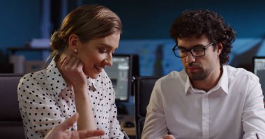 Genç çift ofis çalışanları büyük ofise meslektaşları diğerleri yakınındaki masada otururken onların proje hakkında danışmanlık. Kapalı