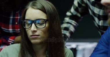 Bir düşünceli gece geç modern ofis alanı içinde onun arkadaşları arasında bilgisayarda çalışan genç güzel kadın, yakın çekim. Ofis çalışanları ve arka plan üzerinde. Portre vurdu